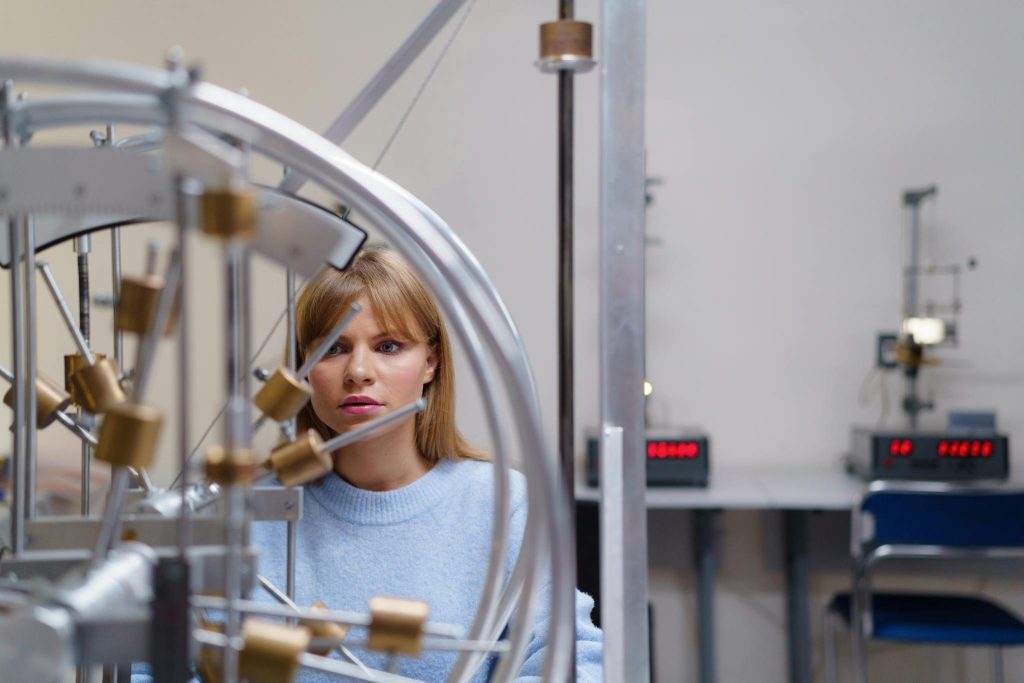 Focused student engaging with physics equipment in a university lab setting, illustrating interactive learning.